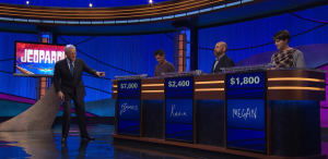 Alex Trebek points at Kevin Bohannon's podium on the April 15, 2019 episode of Jeopardy!, signalling that he has control of the board. Note the white light at the bottom left of the podium.